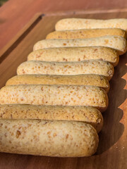 Freshly baked cheese sticks arranged on a wooden board in natural sunlight showcasing crunchy texture and golden color ideal for snacks breakfast or traditional homemade food presentations
