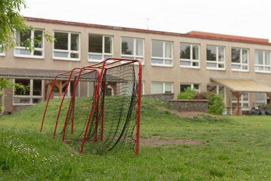 This image shows a vibrant schoolyard with soccer goals and a school building in the background, highlighting the important outdoor space for students to play and engage in activities - Powered by Adobe