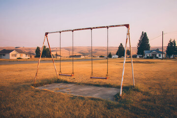 Empty Rusty Swing Set at Sunset on Dry Grassy Field