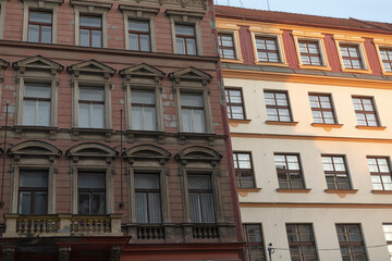 Two architecturally unique facades stand out, emphasizing the contrasting materials and diverse styles of adjacent historic buildings situated within a vibrant urban environment