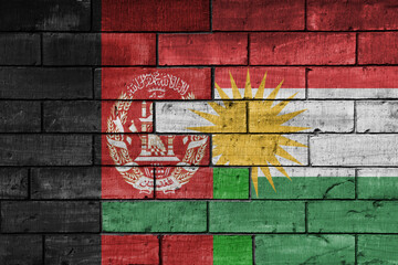 colourful painted big national flag of afghanistan and flag of kurdistan on a massive old brick wall background. concept