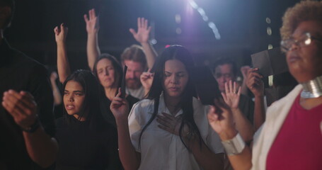 Fototapeta premium Diverse congregation raising offering envelopes during emotional prayer, immersed in worship and deep spiritual reflection