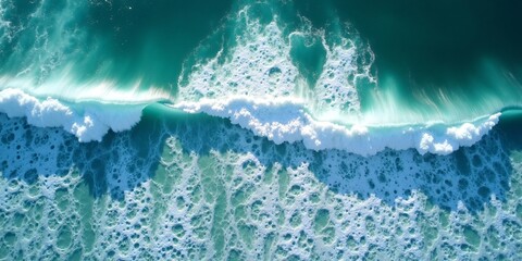 A top-down aerial view of ocean waves crashing against the shore