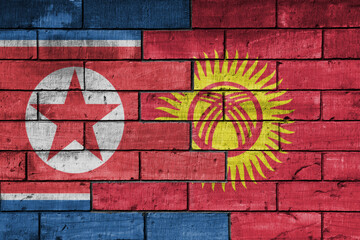 colourful painted big national flag of north korea and flag of kyrgyzstan on a massive old brick wall background. concept