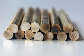Colored metal rods with a cross-sectional texture, arranged on a gray metallic surface reflecting the object