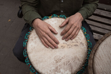 Male hands playing an African drum djembe outdoors in autumn