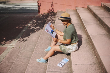 Young Woman Enjoying Leisurely Reading While Sitting Outdoors on Steps in Sunny Weather