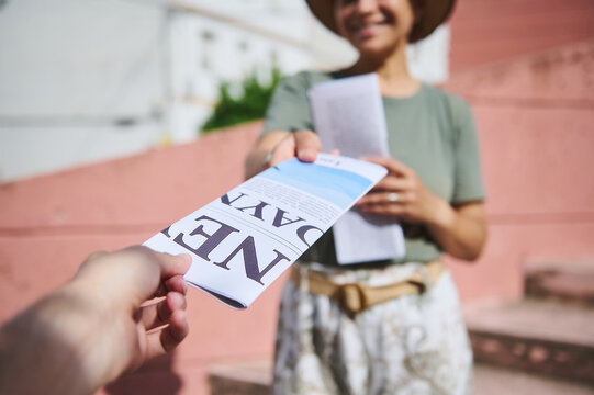 Person Handing Out Flyers Outdoors on a Sunny Day in a Public Space