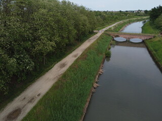 Fototapeta premium Wide drone view of Canale Cavour weaving through Novara’s countryside, vital to Piemonte’s vast agricultural irrigation network.