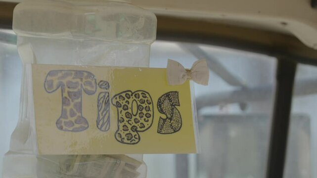 This video shows a hand drawn "tips" sign on a clear plastic jar. 