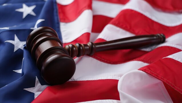 Wooden gavel resting on a textured American flag, symbolizing justice, law, and the U.S. legal system with patriotic and judicial themes. - Powered by Adobe