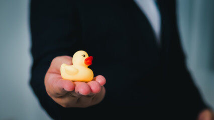 Business hand holding rubber duck office setting creative content playful environment close-up perspective
