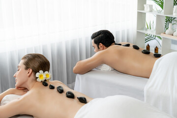 Hot stone massage at spa salon in luxury resort with day light serenity ambient, blissful couple...