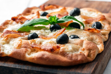 Pinsa romana con guanciale croccante, mozzarella e olive nere, cibo italiano 