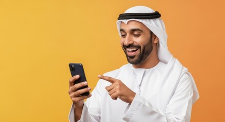 Happy middle eastern man using smartphone in traditional wear against yellow background