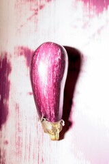Colorful graffiti displays a striking eggplant design against a textured wall, blending street art with playful imagery, bringing life to the urban environment during the day
