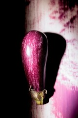 An eye-catching eggplant painted on a wall catches the eye, blending colors and textures in a narrow alley during twilight. This artwork transforms the ordinary into extraordinary
