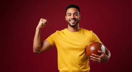 Confident man celebrating victory with basketball on red background