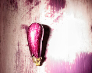 A colorful eggplant design stands out against a textured wall, reflecting the artist's unique style. This artwork brightens up an urban setting with its vibrant hues and creativity