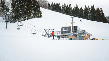 A scenic view of the ski lift gondola at Gala Yuzawa resort in Niigata, Japan. Snow-covered slopes and bare trees line the winter landscape, inviting visitors for skiing and alpine adventures.