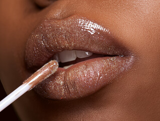 macro shot of beige brown glitter lip gloss being applied to full lips on deep skin, sparkling texture, soft glam lighting 