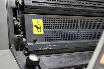 Warning label affixed to printing platen covers in a printing house. Careful hands can get stuck. danger of breaking fingers when the machine is in print. Work safety
