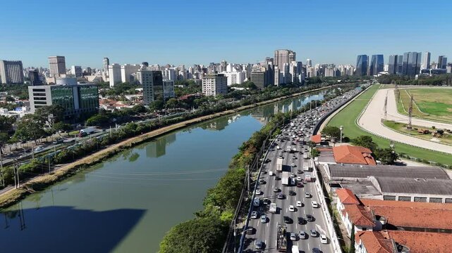 Tomada a&eacute;rea panor&acirc;mica da Marginal Pinheiros em S&atilde;o Paulo revela tr&acirc;nsito intenso, edif&iacute;cios modernos e o rio margeando a movimentada via urbana