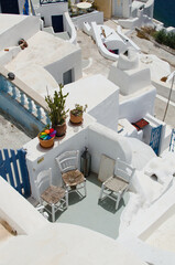 Small white patio with rustic chairs and potted plants overlooking narrow alleys and traditional...