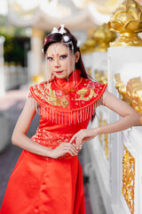 Woman in elegant red cheongsam posing confidently at traditional temple