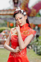 Playful woman in traditional red outfit with rabbit-themed makeup outdoors