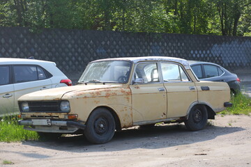 An old rusty Soviet car is parked on the side of the road, Krzhizhanovsky Street, St. Petersburg,...