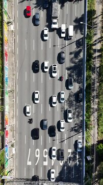 Vis&atilde;o a&eacute;rea vertical de ve&iacute;culos em um dia de tr&acirc;nsito carregado. A imagem mostra carros enfileirados em diversas faixas, retratando o caos urbano em uma grande cidade brasileira