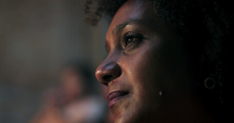 Close-up of woman with curly hair, emotionally moved during spiritual moment in church, illuminated...
