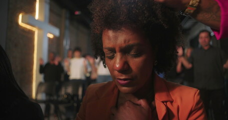 Close-up of congregation members receiving a blessing during a church event, with hands placed on...