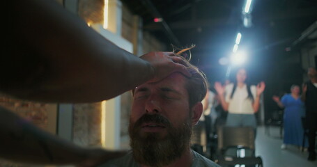 Man receiving prayer support, head touched by hand, emotional moment of faith and spiritual intervention, people praying in background, Christian faith