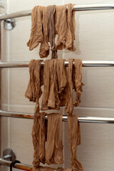 Yellow nylon socks drying on a heated towel rail in a bathroom, showcasing everyday laundry care at home