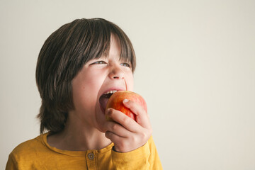 Boy taking a big bite of an apple with copy space