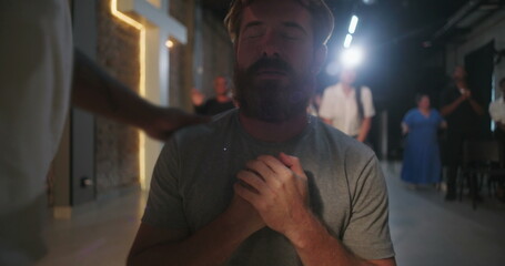 Man in emotional prayer, receiving spiritual support, hands on chest, eyes closed in devotion,...