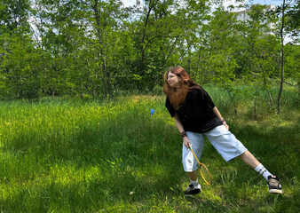 Teen girl in mid-air while playing badminton in sunny green meadow. Youth outdoor activity in summer park. Active girl enjoying outdoor activity in nature, summer lifestyle concept.