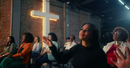 Hispanic woman of African descent with emotional expression, hands raised in worship as part of...