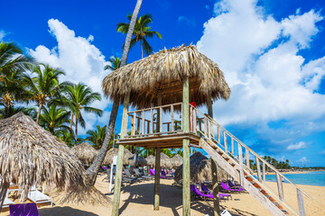 Lifeguard tower with straw roof on clean sandy beach with palm trees and Atlantic Ocean view. Dominican Republic. Punta Cana. 