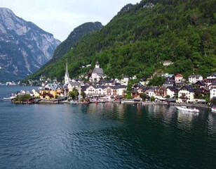 Fototapeta premium Panoramic view of a picturesque alpine village nestled on a lake shore, with mountains in the background
