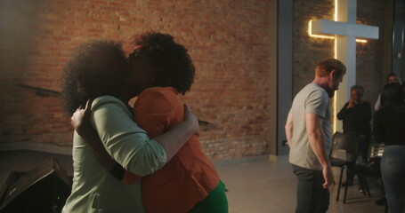 Congregation members sharing an emotional embrace during a Christian event, expressing love and...