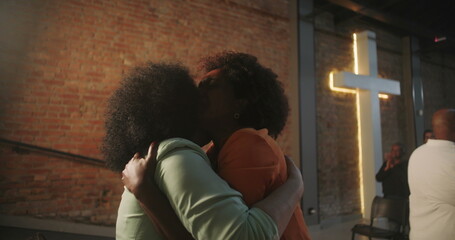 Congregation members sharing an emotional embrace during a Christian event, expressing love and...