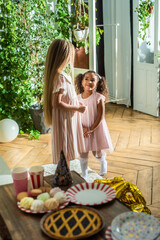 birthday party. Two little girls happily play with colorful balloons in their home