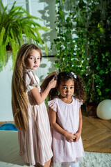 A little girl is gently combing the beautiful hair of another little african american girl