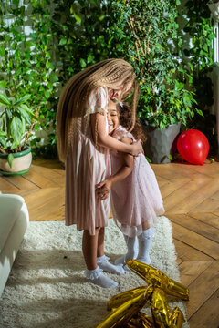 girls, Sisters joyfully embracing each other in a lush and cozy living space filled with warmth