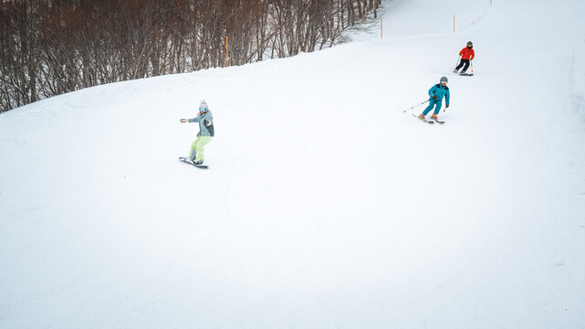 Skiers enjoy the slopes of Gala Yuzawa with stunning views of Ishiuchi Maruyama and Yuzawa Kogen in Niigata, Japan, 02142025 Snow-covered mountains and a small town stretch across a scenic winter. - Powered by Adobe