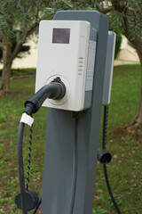 An outdoor electric vehicle charging EV station with an abb logo, featuring a plugged in cable and a gray stand, concept of sustainable transportation and green energy