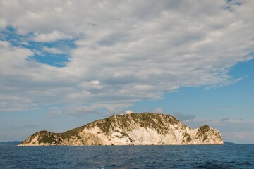Cruising through the stunning waters of Zakynthos, visitors admire the rugged cliffs and lush greenery of the island beneath a gorgeous summer sky, creating a picturesque escape
